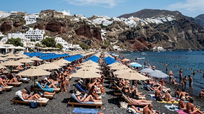 সান্তোরিনির পাথুরে এবং জনাকীর্ণ সৈকতের একটি বাস্তব চিত্র।